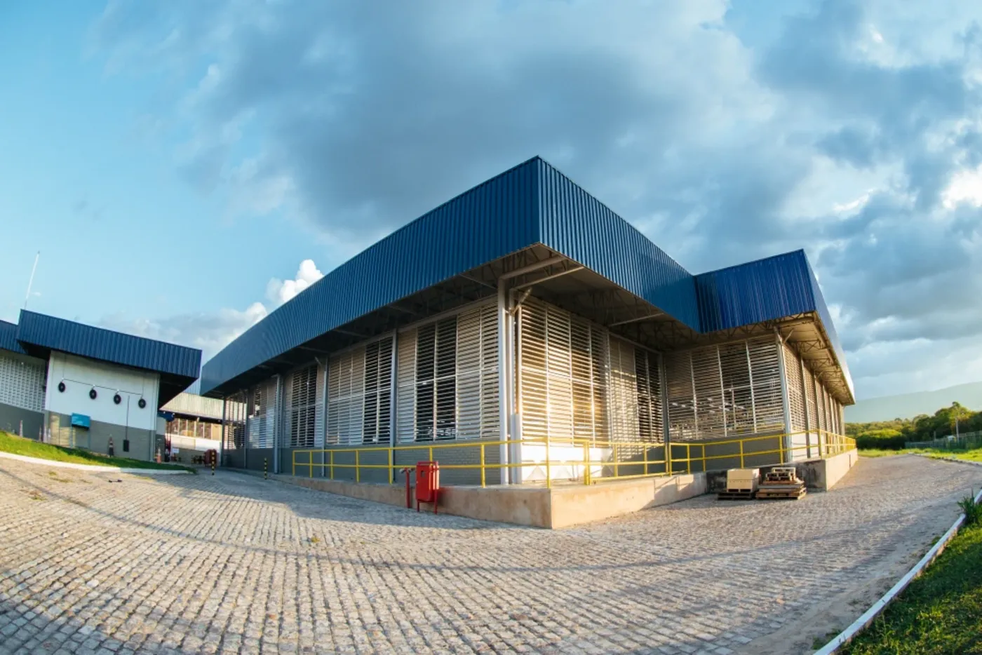Galpão industrial entregue pela Ampla, com estrutura metálica azul e brises verticais em alvenaria